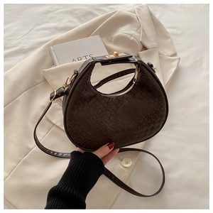 Detail of dark brown crescent bag with woven texture on a white suit and book backdrop