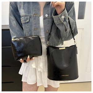 Détail du sac seau en cuir noir avec poignée tressée et sa pochette assortie