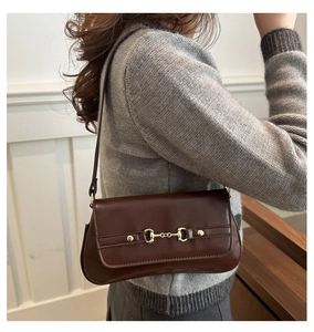 Detail of vintage brown faux leather shoulder bag with golden horsebit metal buckle