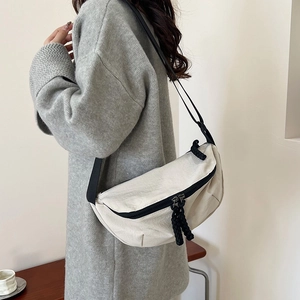 Minimalist beige crescent crossbody bag with adjustable black strap for daily commute