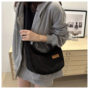 Detail of black corduroy hobo bag showing the cord texture and fashion leather patch
