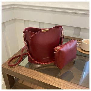 Détail d'un sac seau en cuir bordeaux avec poignée tressée et sa petite pochette assortie