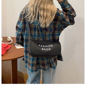 Detail view of the black canvas fashion bag with white typography on a model back