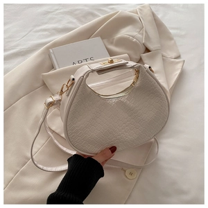 Detail of cream woven texture handbag showing the golden metal lock and leather strap