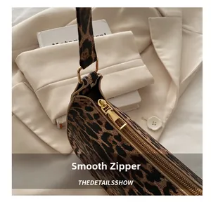 Détail d'une fermeture éclair dorée lisse sur un sac à bandoulière à motif léopard