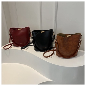 Trois sacs seaux en cuir texturé rouge, noir et marron avec bandoulières tissées et dorures
