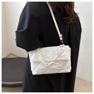 Détail d'un sac à bandoulière matelassé blanc avec chaîne épaisse et finitions dorées