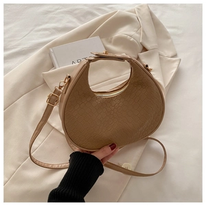 Close-up of khaki crocodile embossed texture and gold hardware on crescent shoulder bag