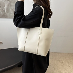 Close-up of minimalist cream tote bag with fine stitching and slim shoulder straps