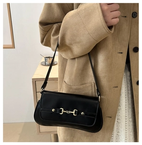 Detail of black underarm bag with iconic gold horsebit buckle on smooth leather
