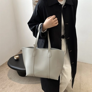 Chic light gray leather tote bag styled with a black trench coat for a modern commute
