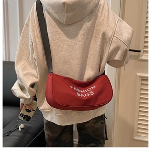 Macro shot of red canvas crescent bag with white Fashion Bags lettering and wide strap