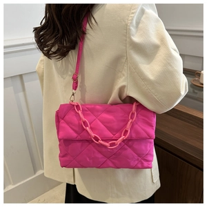 Détail du sac matelassé rose vif avec grosse chaîne en plastique sur blazer beige