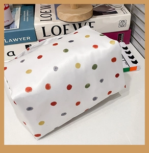 Close-up of a white rectangular makeup bag featuring colorful polka dots and zip closure