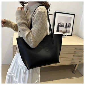 Detail of minimalist black tote bag featuring unique geometric stitching and soft leather texture