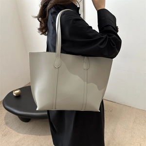 Beige faux leather tote bag showcased on a shoulder in a minimalist indoor setting
