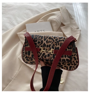 Detail of vintage leopard print handbag with red leather strap and golden horsebit hardware