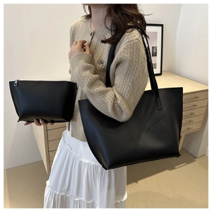 Detail view of large black tote bag and matching pouch in minimalist synthetic leather