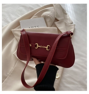 Detailed view of luxury burgundy leather shoulder bag featuring gold horsebit hardware buckle