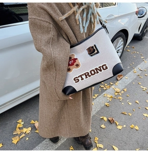 Detail of vintage canvas tote bag with embroidered bear and varsity patch in autumn street setting