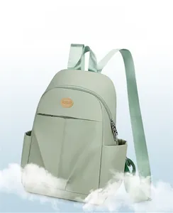 Detailed side view of a light green water-resistant nylon backpack with logo and side pockets