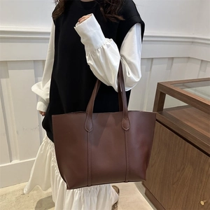 Detail view of large dark brown leather tote bag with fine stitching and matte finish