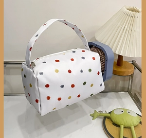Detailed view of colorful polka dot plush makeup bag with silver zipper and handle
