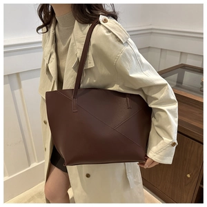 Close-up of contrast stitching on dark coffee leather tote bag worn with beige coat