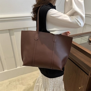Detail of a large dark brown faux leather tote bag worn over the shoulder for daily commute