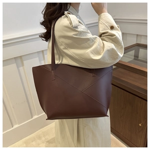 Macro view showing the minimalist deep brown matte leather tote with geometric stitching