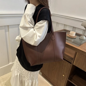 Brown leather tote bag worn by model in a cozy indoor setting with vintage vibes