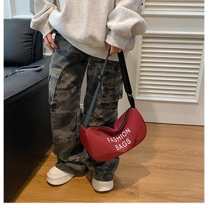 Detail of red crescent nylon shoulder bag with adjustable strap and fashion lettering
