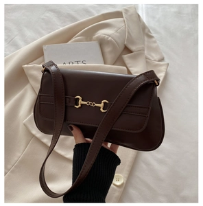 Detail of a dark brown leather underarm bag with a golden horsebit buckle hardware