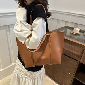 Brown leather tote bag worn by model in a minimalist interior for daily commuting style