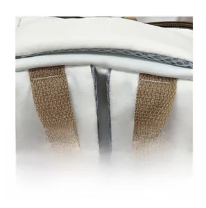 Close-up of canvas backpack with reinforced stitching and brown woven handle strap