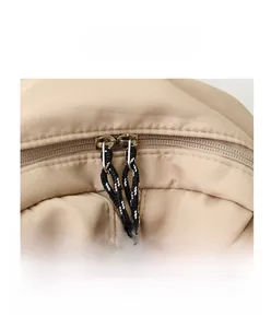 Detail of sturdy dual-zipper closure and woven cord pullers on beige nylon backpack