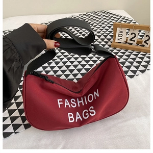 Detail of burgundy crescent crossbody bag with adjustable strap and fashion print