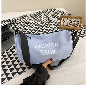 Detail of light blue crossbody bag featuring white Fashion Bags text and black strap