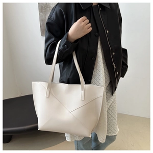 Detail shot of a large cream tote bag with geometric stitching and slim shoulder straps