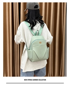 Detail showing mint green nylon backpack back straps on a model with a round logo patch