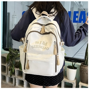 Close-up of white multi-pocket nylon backpack with embroidered logo on model back