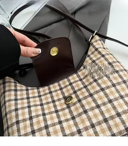 Detail of golden magnetic clasp on vintage brown checkered canvas shoulder bag