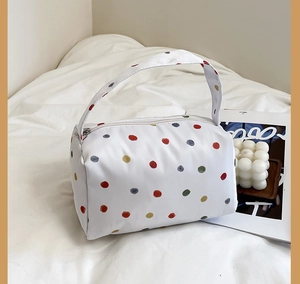 Minimalist white plush makeup bag with colorful polka dots and a sturdy top handle
