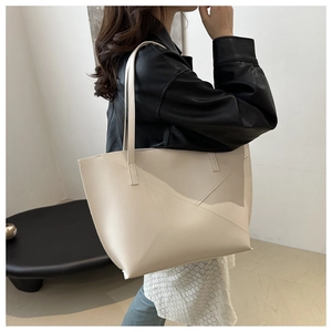Detail view of cream tote bag with geometric leather patchwork and slender straps