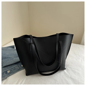 Detail of minimalist black tote bag featuring geometric stitching and matte PU leather texture
