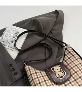 Detailed shot of brown plaid canvas tote bag with 3D teddy bear patch on leather flap