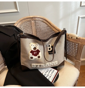Detail of canvas tote bag with plush bear patches and leather trim on vintage chair