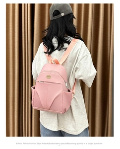 Back view of a woman wearing a pink water-resistant nylon backpack with large capacity