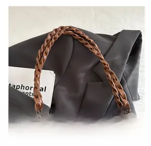Dettaglio della borsa tote in peluche leopardata con manico intrecciato su giacca grigia