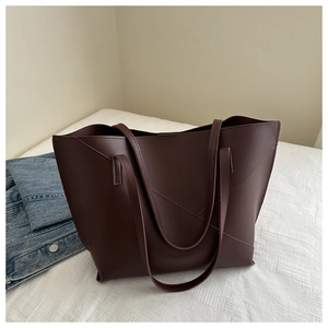 Detail view of deep coffee leather tote bag with geometric stitching and slim straps